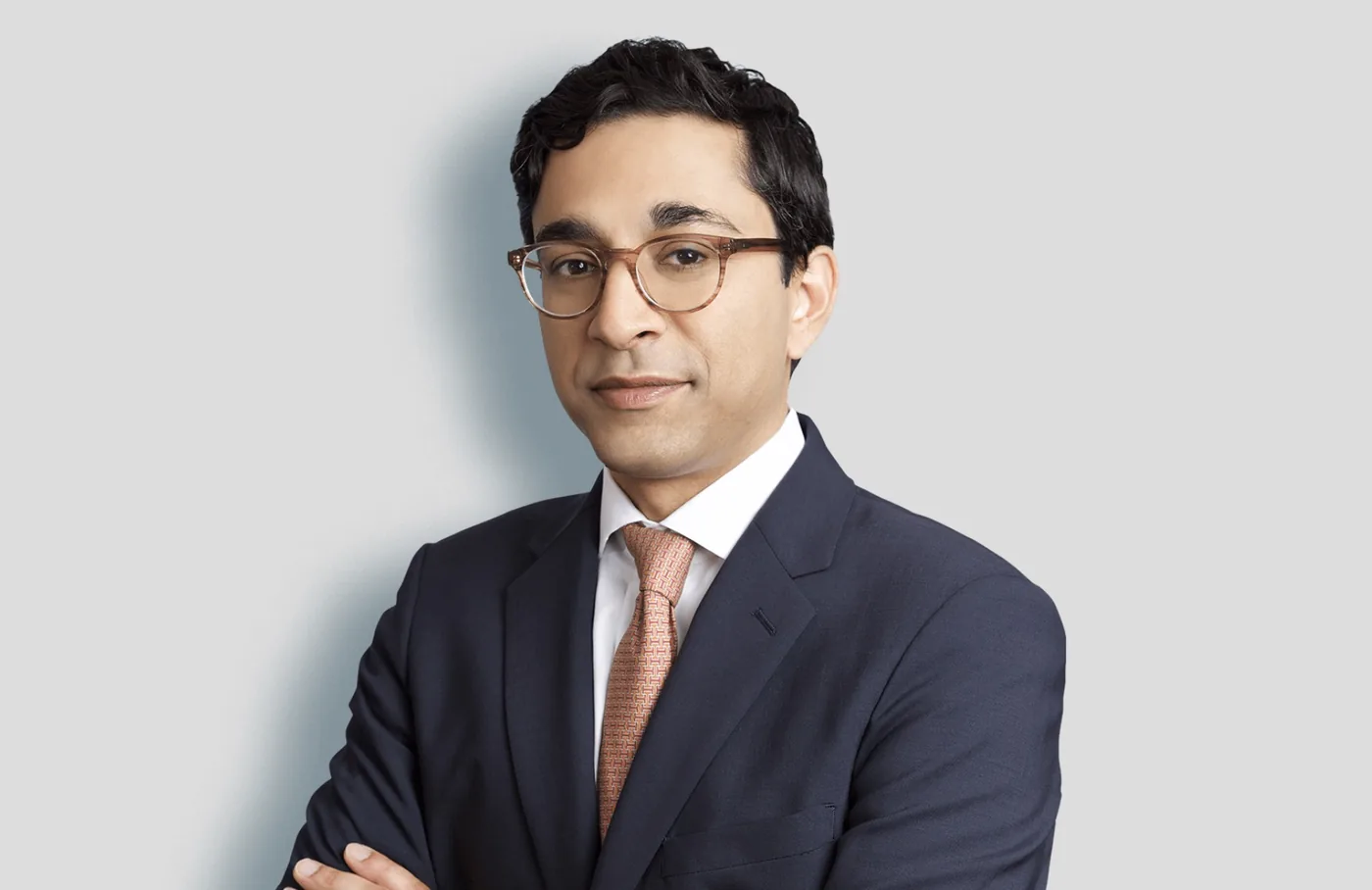 Team headshot of a man in glasses on a light gray backdrop